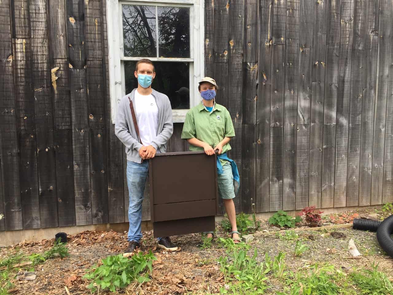 Two students standing with masks beside the bat box they built